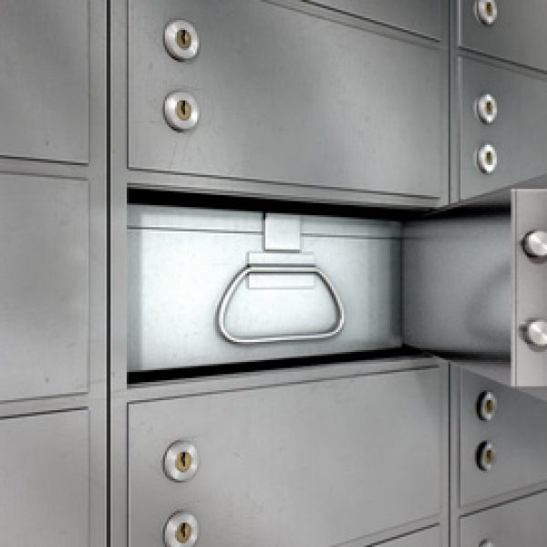 A closeup of a wall of closed metal safety deposit boxes with one open revealing its contents inside